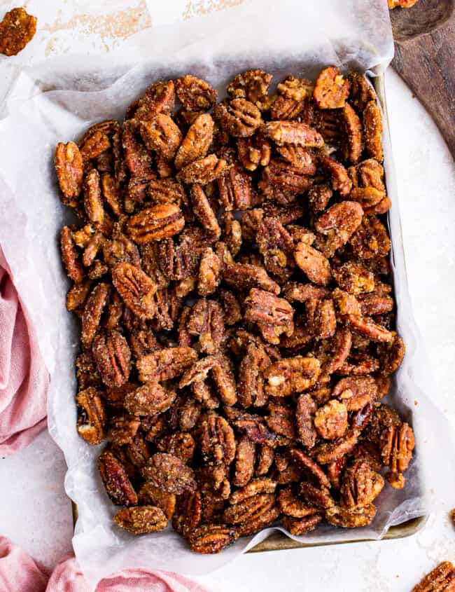 overhead image of candied pecans on a baking sheet lined with parchment paper