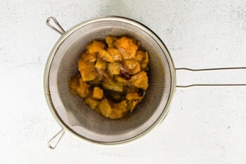 straining apple syrup mixture in wire mesh sieve