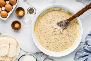 sausage gravy in a white skillet with a wood spoon