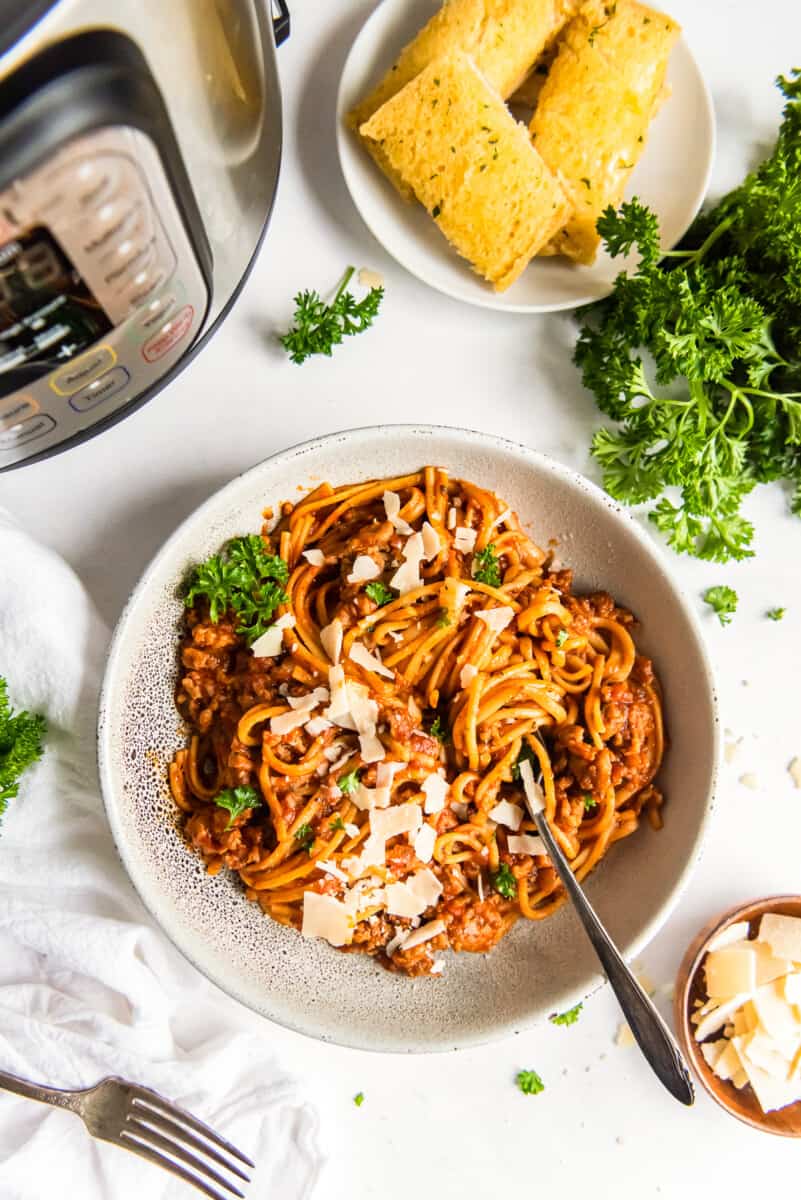 spaghetti topped with herbs and parmesan cheese in a white bowl with a fork