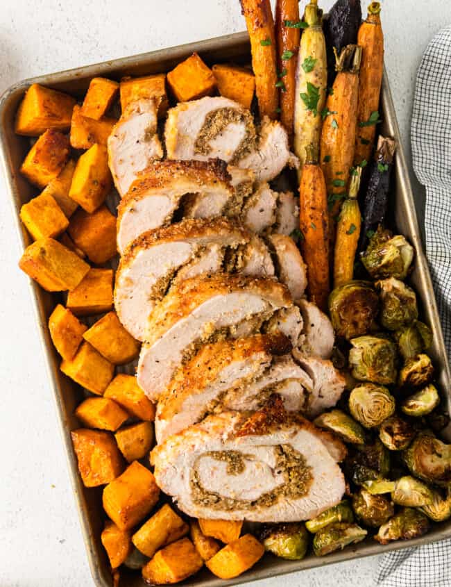 roasted sweet potatoes, carrots, and Brussels sprouts and sliced turkey roulade on a sheet pan