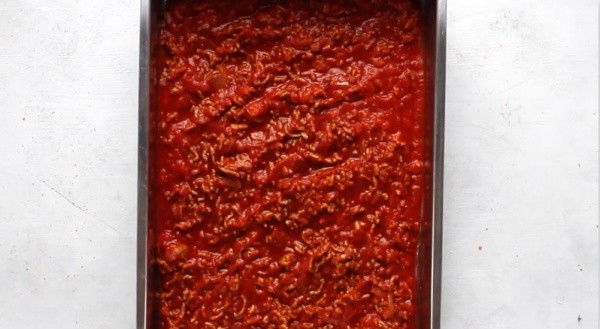 meat marinara sauce in the bottom of a baking dish