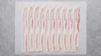 overlapping slices of bacon on parchment paper.