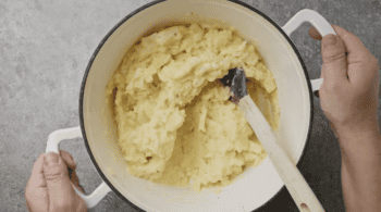 creamy mashed potatoes in a Dutch oven with a rubber spatula.