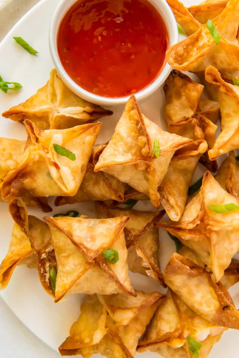 crab rangoon on white platter with sweet and sour sauce