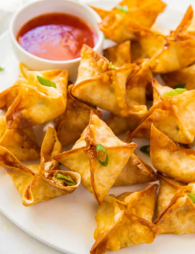 crab rangoon on white platter with sweet and sour sauce