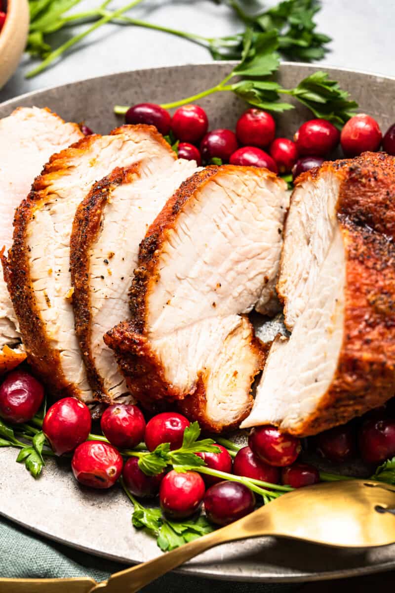 side view of slices of deep fried turkey on a serving platter with cranberry and herb garnishes