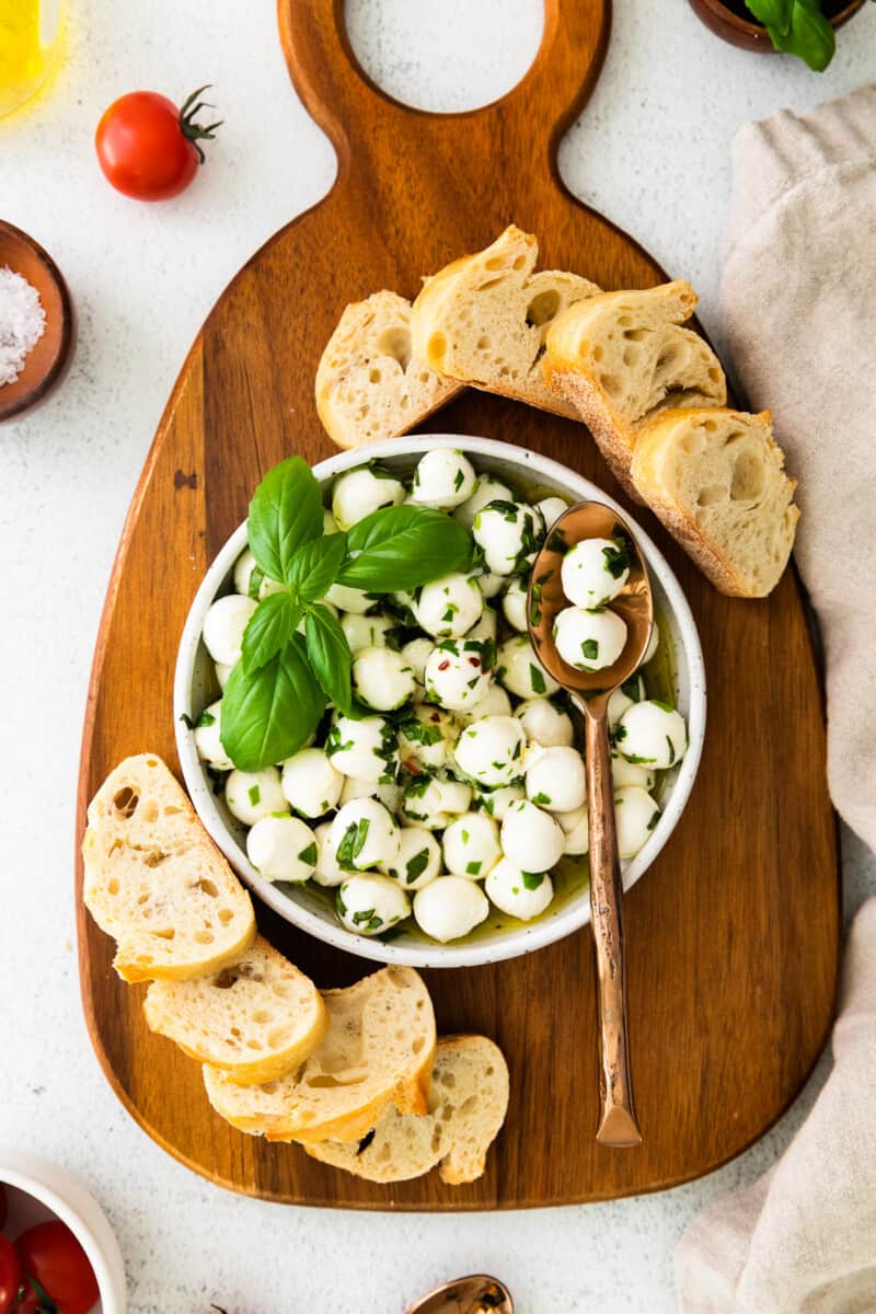 herb marinated mozzarella in white bowl with spoon