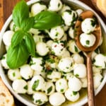 herb marinated mozzarella in white bowl with spoon