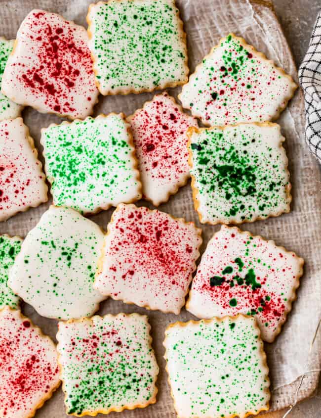 square sugar cookies topped with white icing and green and red splatter decoration