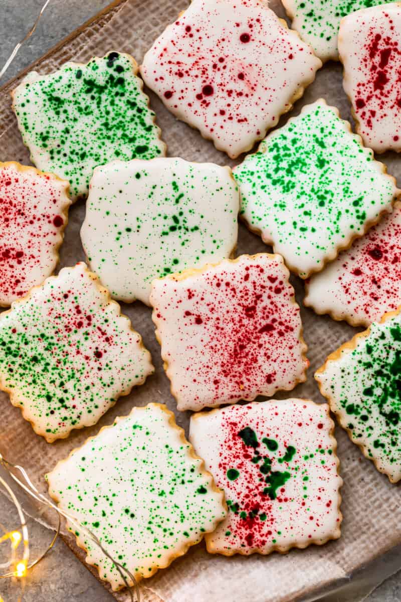 square sugar cookies topped with white icing and green and red splatter decoration