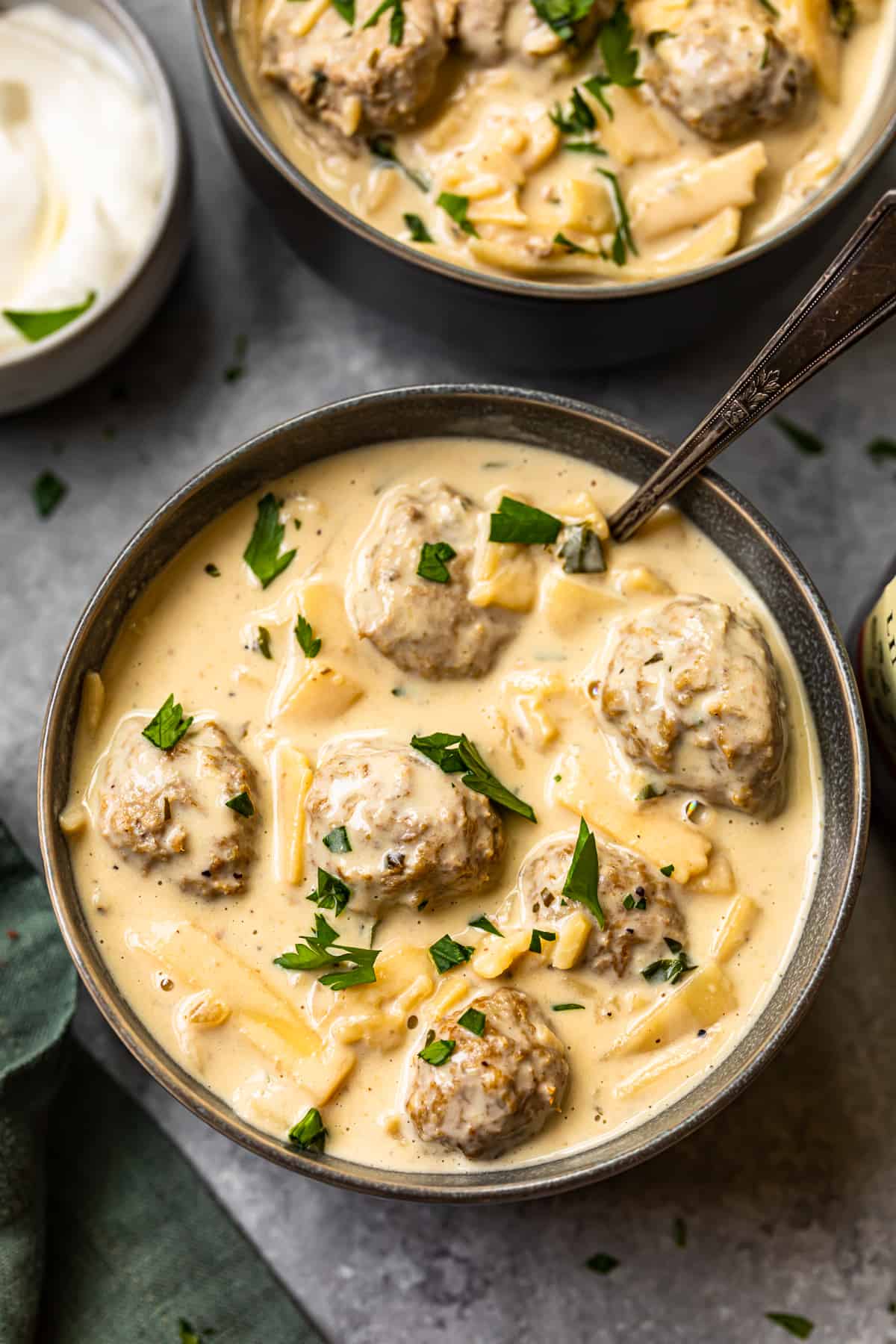 swedish meatball soup in a black bowl with a spoon.