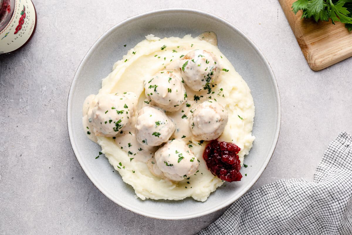 overhead image of crockpot swedish meatballs on top of mashed potatoes in a bowl