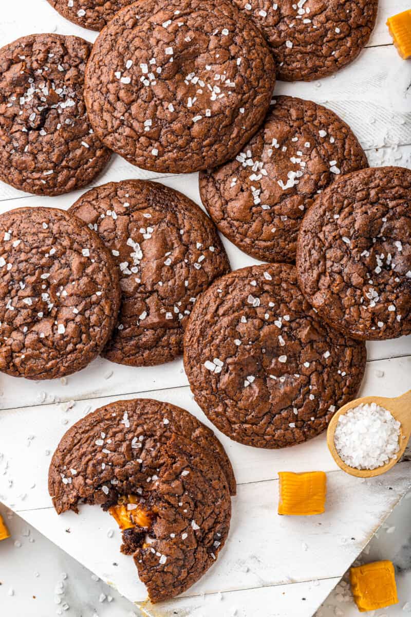 overhead image of chocolate cookies topped with sea salt with a bite taken from one cookie showing the caramel center