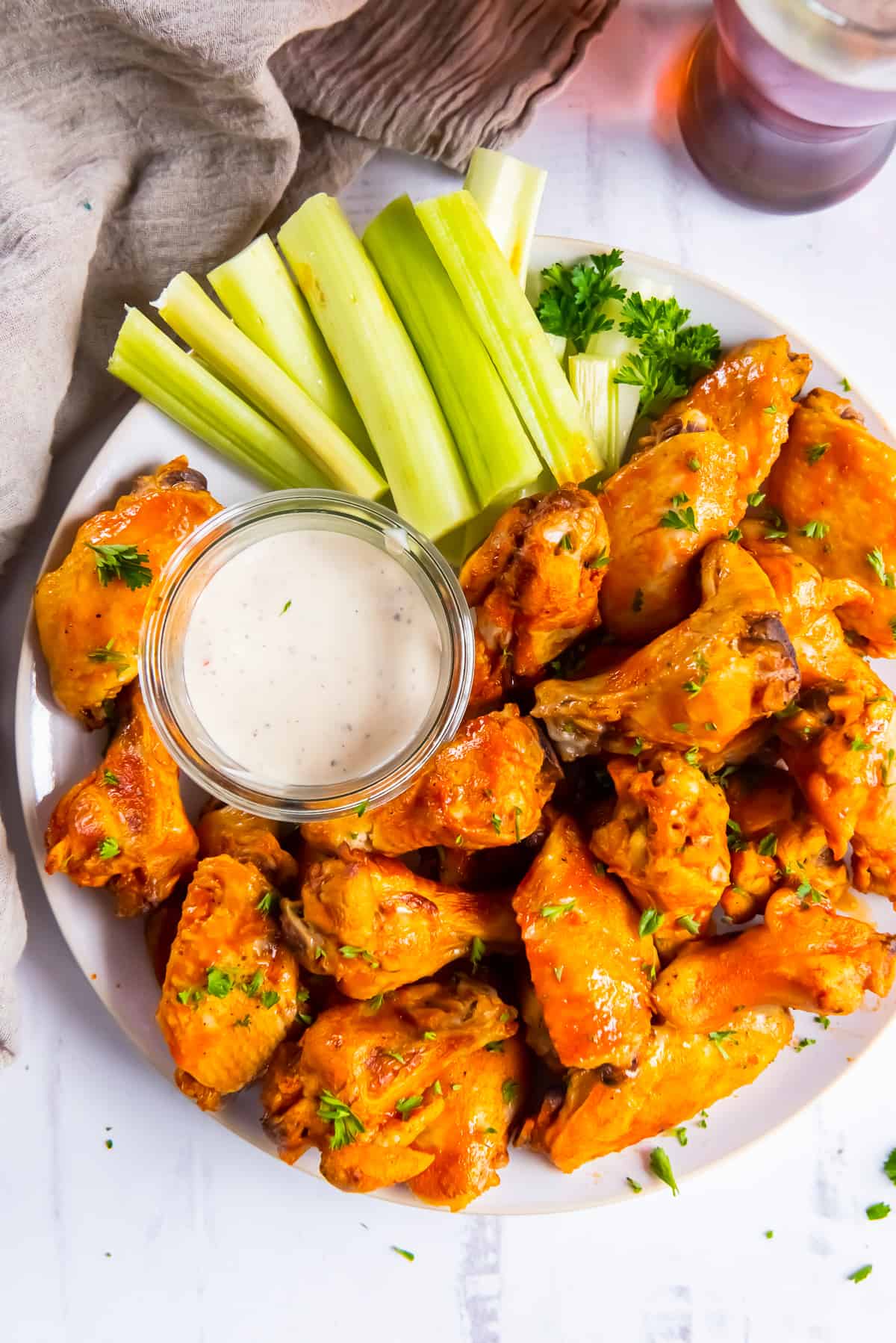 A platter of buffalo wings with ranch and celery.