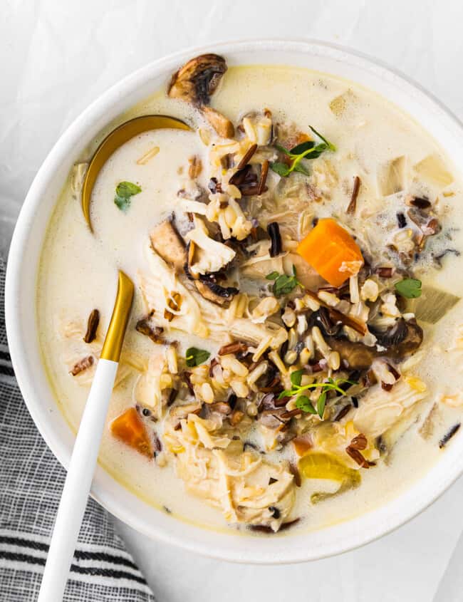 crockpot chicken wild rice soup in a white bowl with a spoon