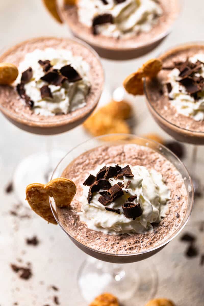 frozen french silk pie cocktails in glasses topped with whipped cream and chocolate shavings and garnished with baked pie crust cookies