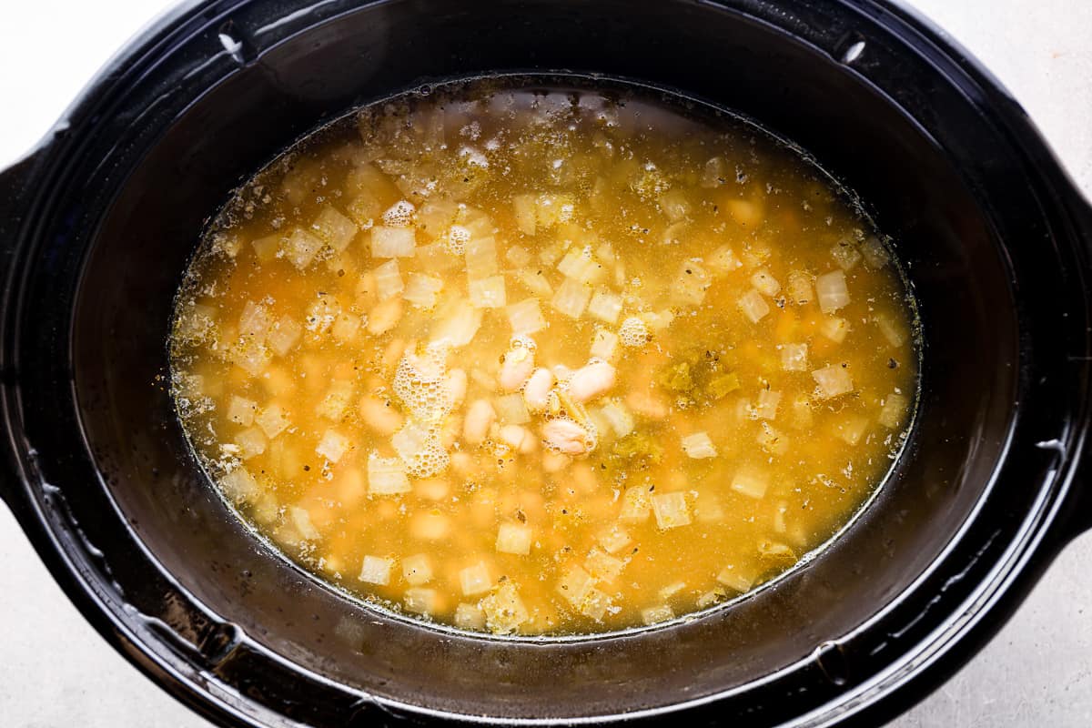 White chicken chili cooking in a slow cooker.