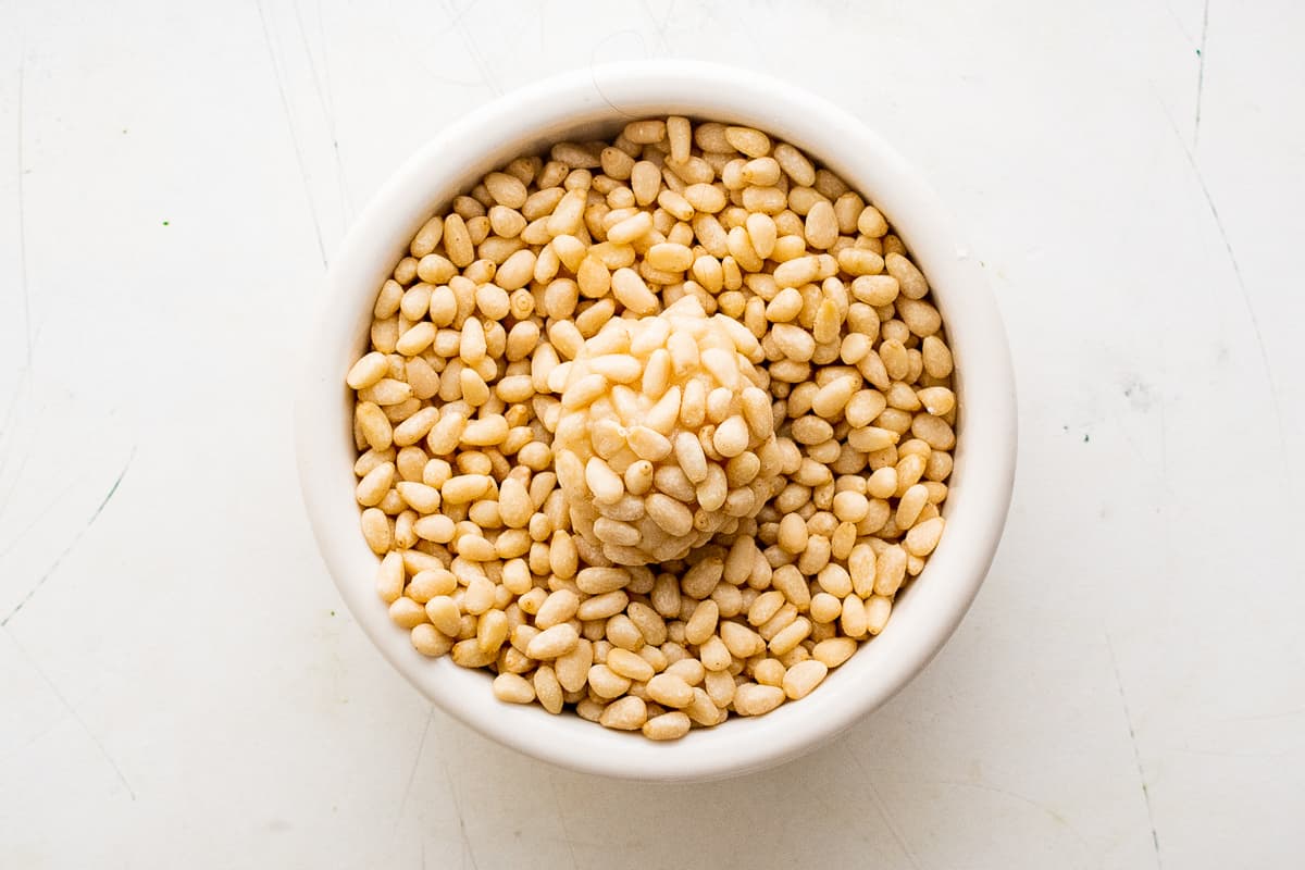 cookie dough ball in a bowl of pine nuts