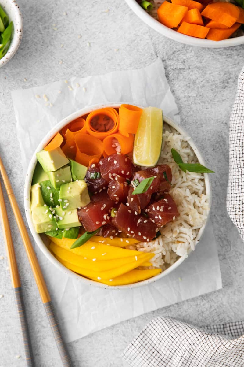 tuna poke bowl in a white bowl with chopsticks.