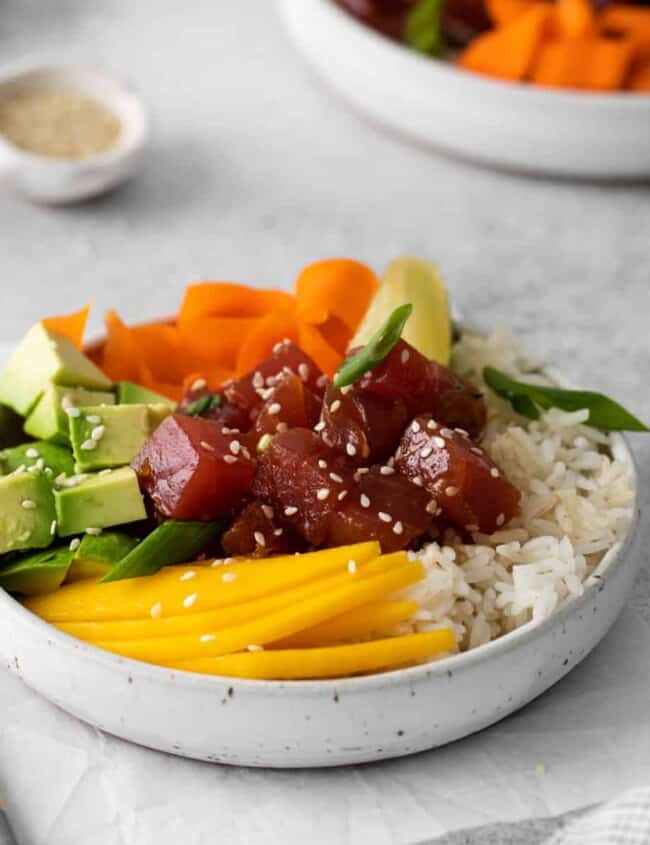 tuna poke bowl in a white bowl with chopsticks.