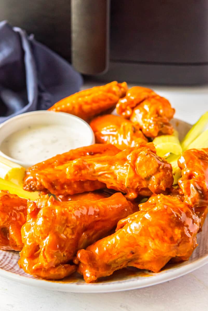 buffalo chicken wings, sliced carrots, sliced celery, and dressing in a white bowl on a white plate