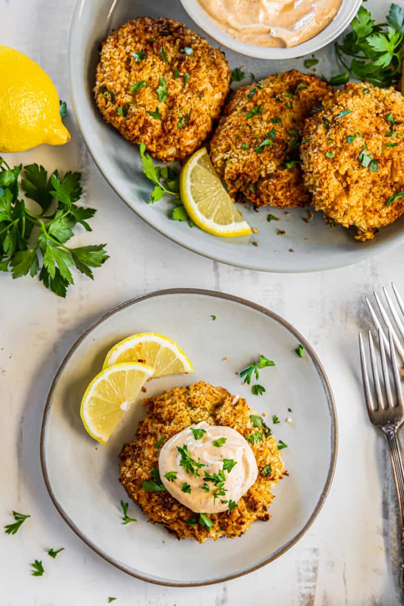 crab cake on a plate topped with sauce and garnished with lemon slices