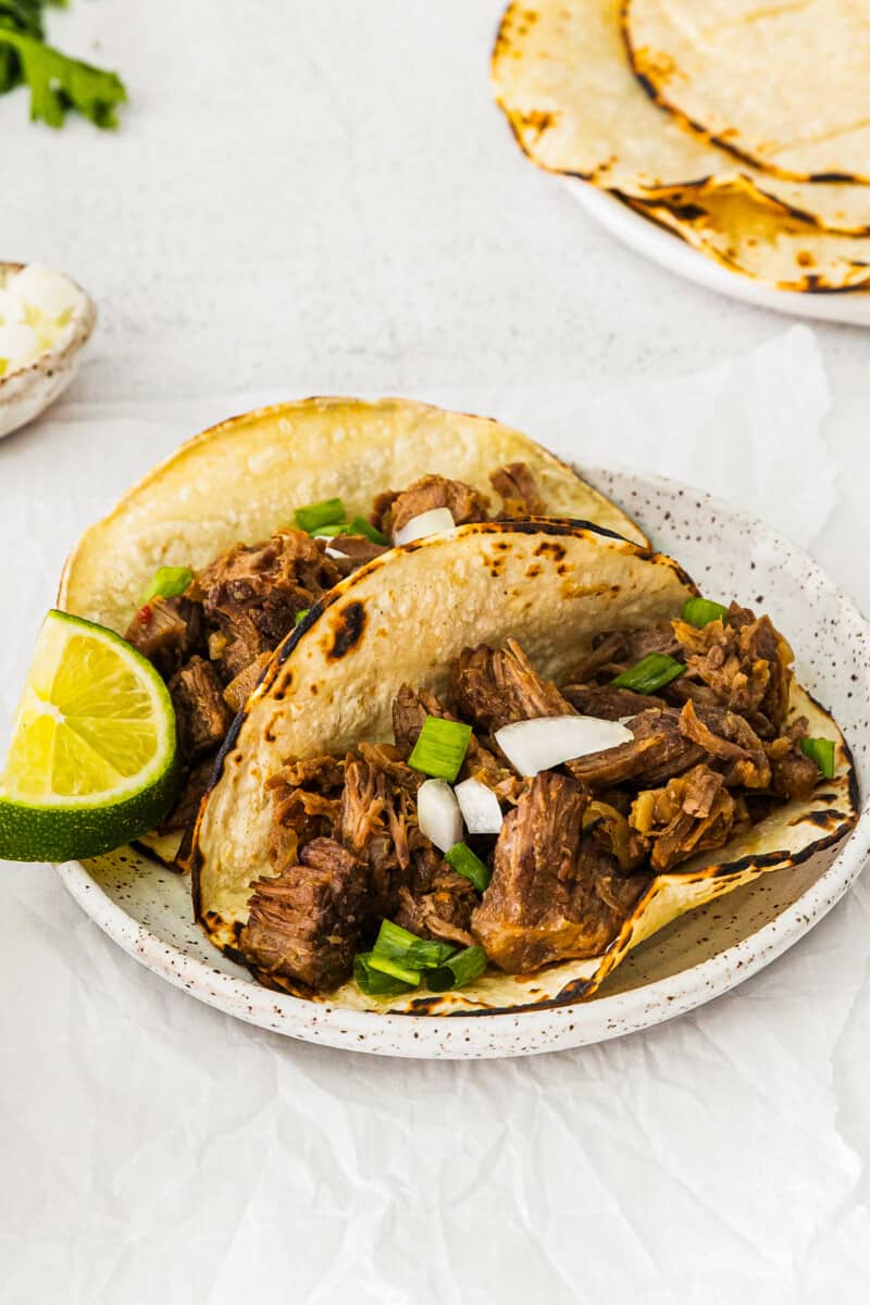 2 beef carnitas tacos on a white plate