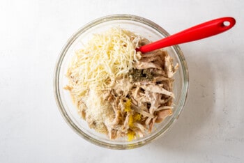 chicken alfredo lasagna roll ups filling in a glass bowl with a spatula