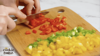 a person cutting bell peppers into chunks with a knife.