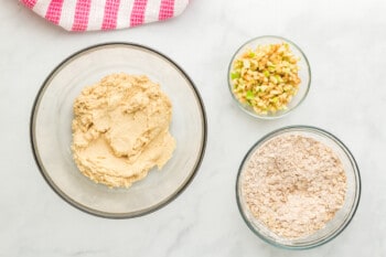 wet ingredients in a glass bowl, dry ingredients in a glass bowl, and diced apple in a glass bowl