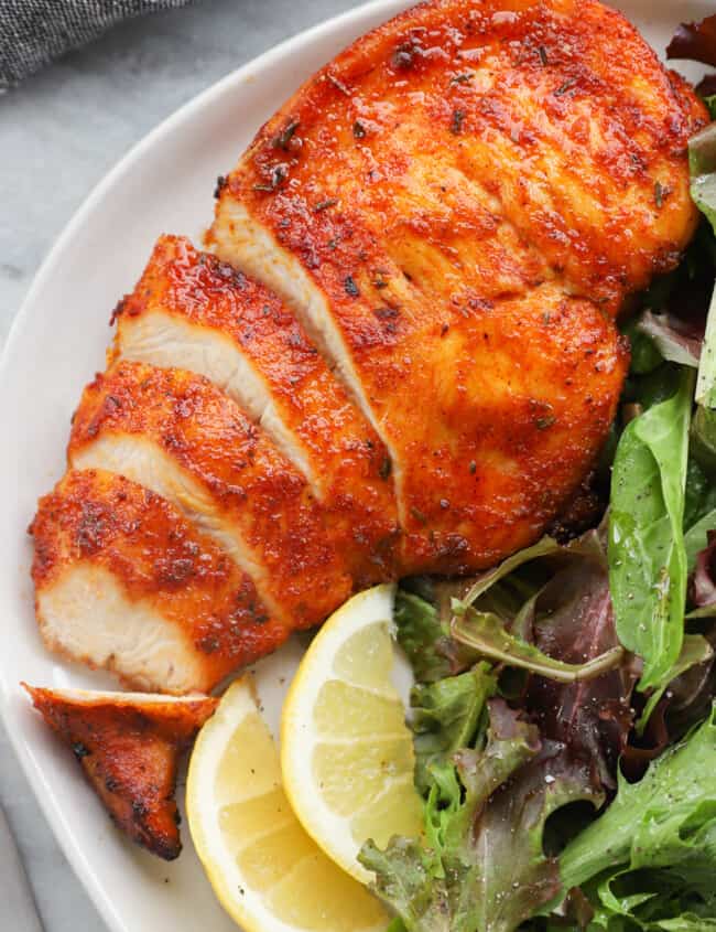 sliced chicken breast on a white plate with salad