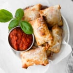 overhead image of pizza rolls in a white bowl with pizza sauce in a metal bowl