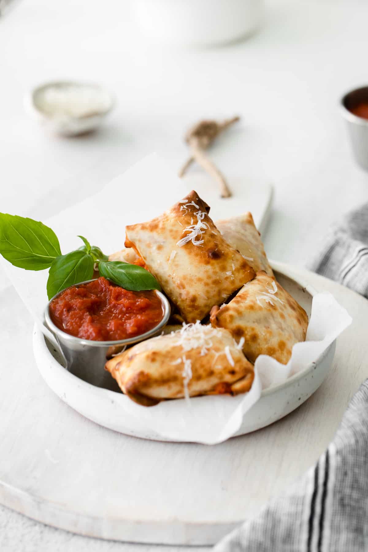 pizza rolls in a white bowl with pizza sauce in a metal bowl