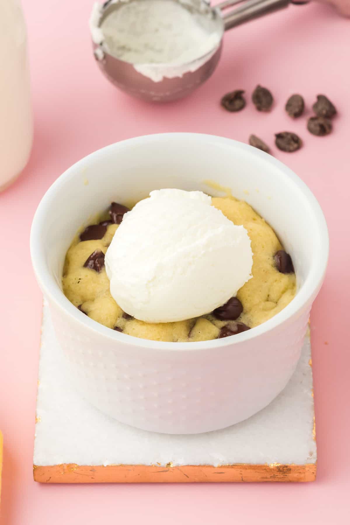 chocolate chip cookie in a mug topped with a scoop of vanilla ice cream