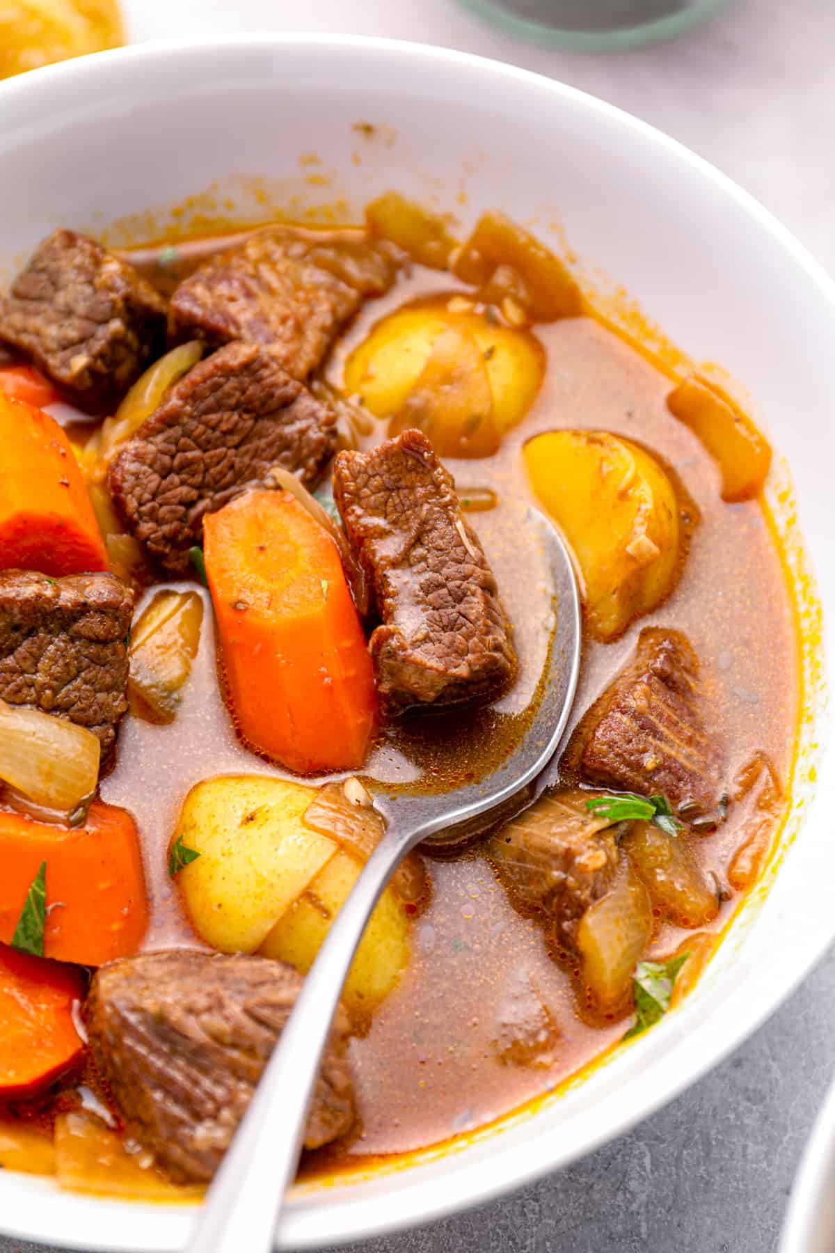 beef stew in a white bowl with a spoon