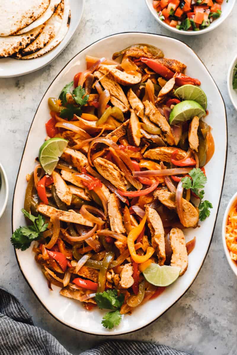 chicken, bell pepper, and onion fajita mixture on a white serving platter