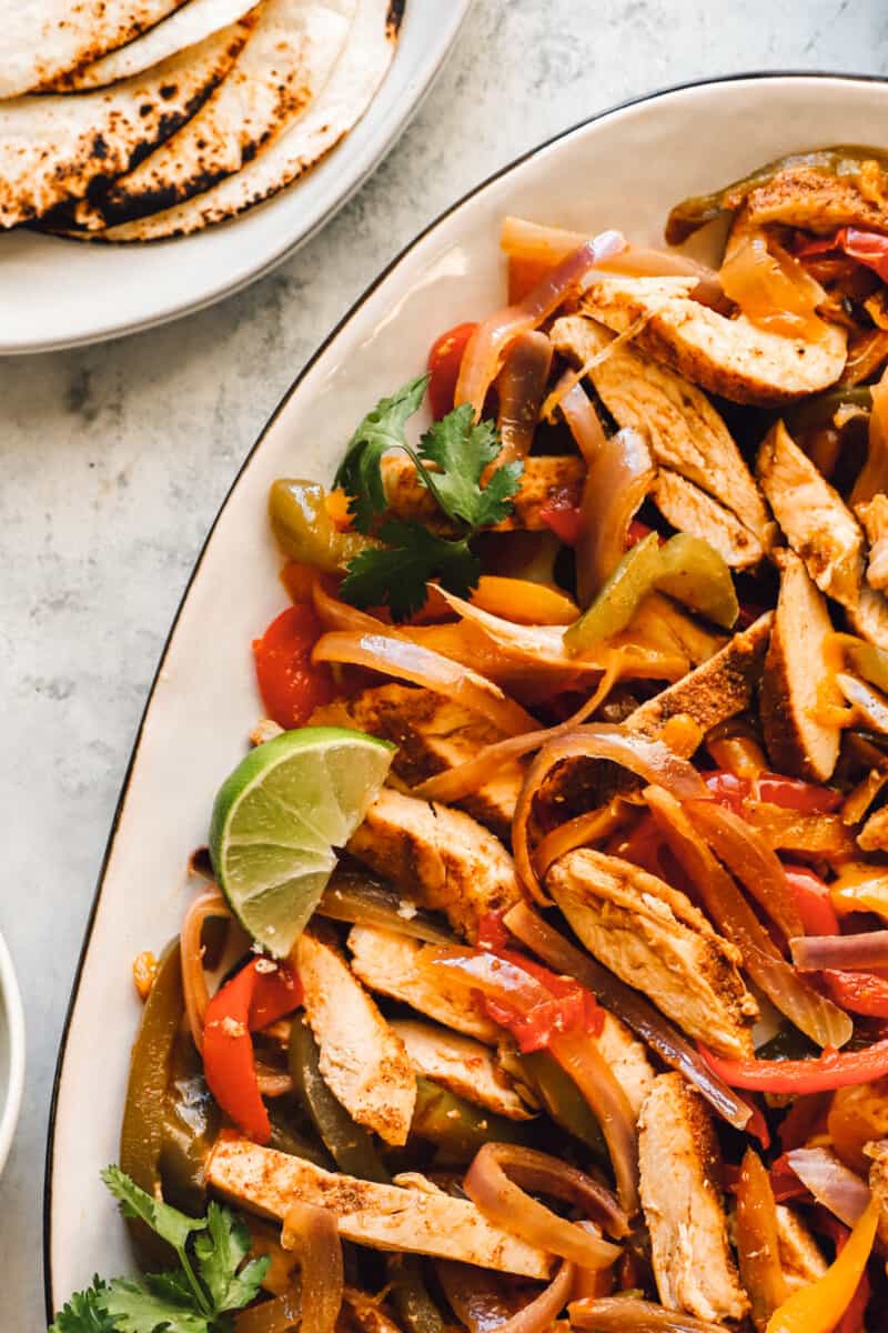 chicken, bell pepper, and onion fajita mixture on a white serving platter