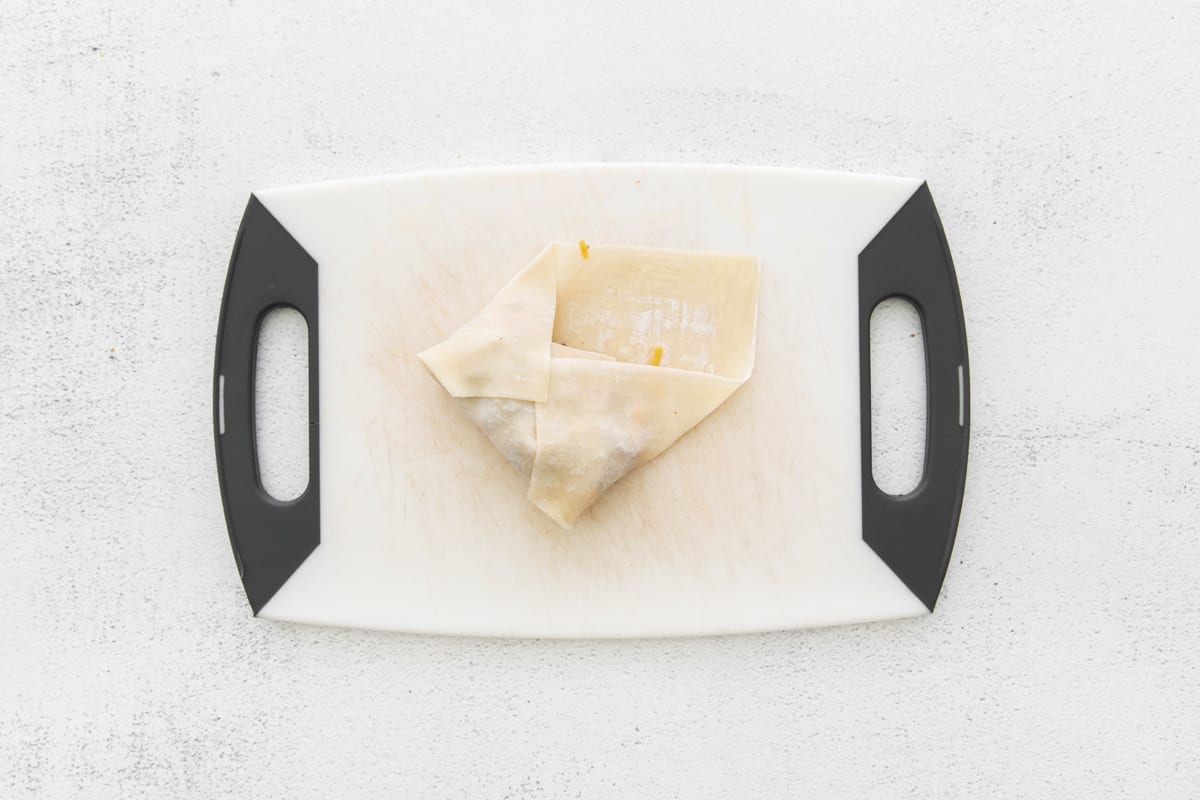 a folded piece of pastry on a white cutting board.