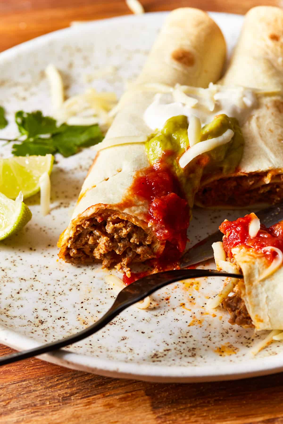 beef taquitos on a white plate with a fork.