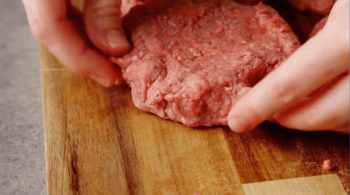 sealing a burger patty filled with cheese.