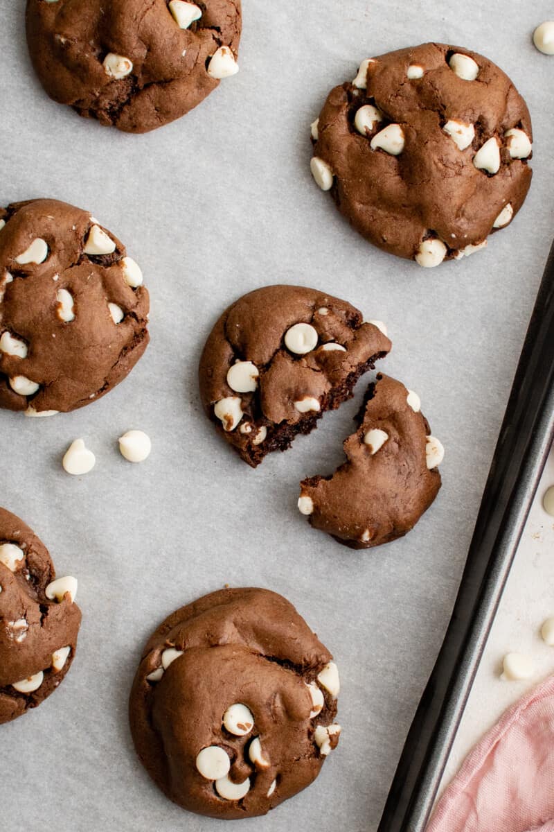 overhead view of a chocolate cake mix cookie broken in half on a baking sheet.