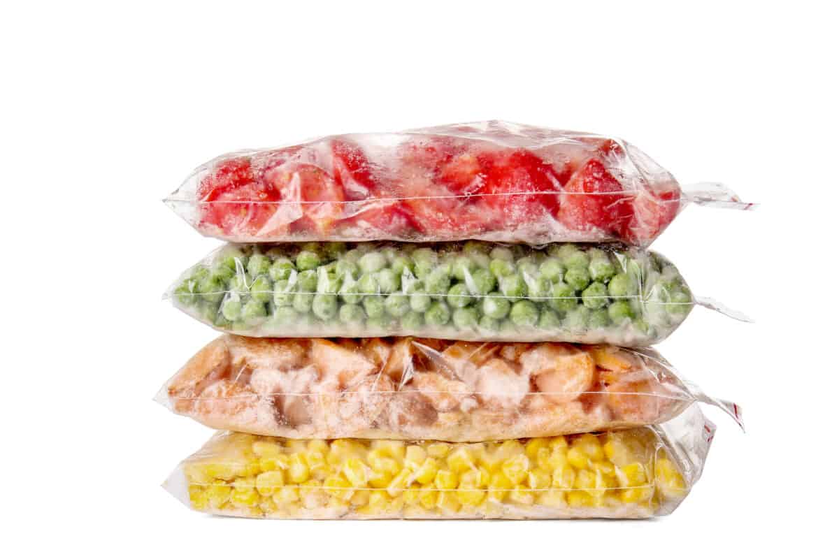 A stack of plastic bags filled with different kinds of vegetables.