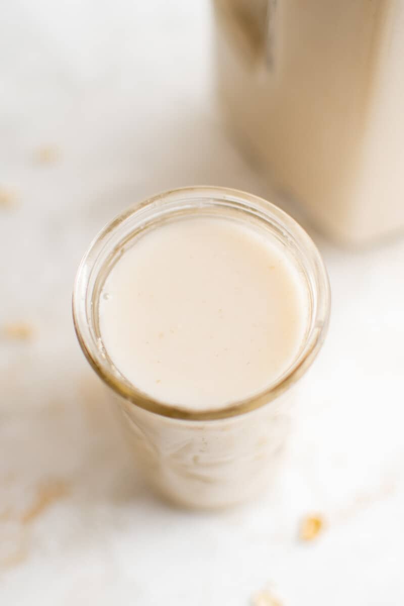 how to make oat milk: a glass full of oat milk from an overhead angle.