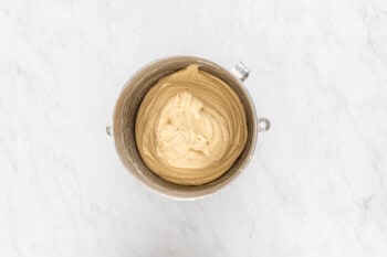 peanut butter icing on bakery style cinnamon rolls on a marble surface.