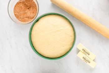 Bakery-style cinnamon rolls ingredients arranged in a bowl on a marble table.