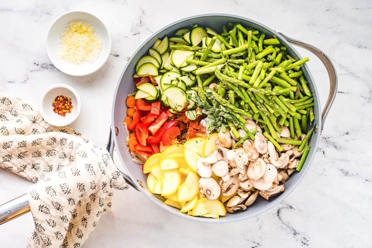 A mix of chopped vegetables in a sauté pan before cooking.