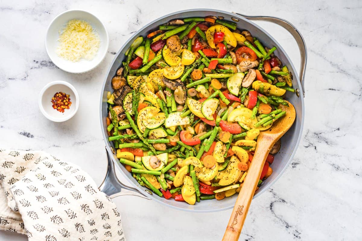 satueed vegetables in a saute pan after cooking with a wood spoon.