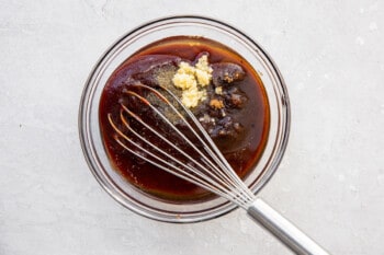 sauce for crockpot bbq chicken in a glass bowl with a whisk.