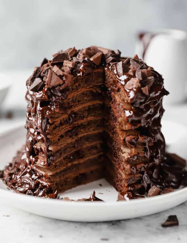 A delectable stack of chocolate pancakes, warm and fluffy, is delicately placed on a pristine plate.